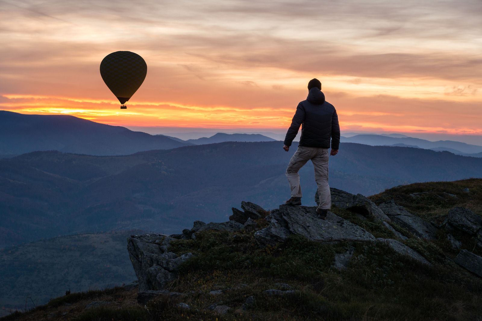 nttdata-solutions.comwp-contentusermediaHeader_Hiker-on-mountain-peak-with-air-balloon-at-sky-sunset-sundown-20231213-GLO-EN